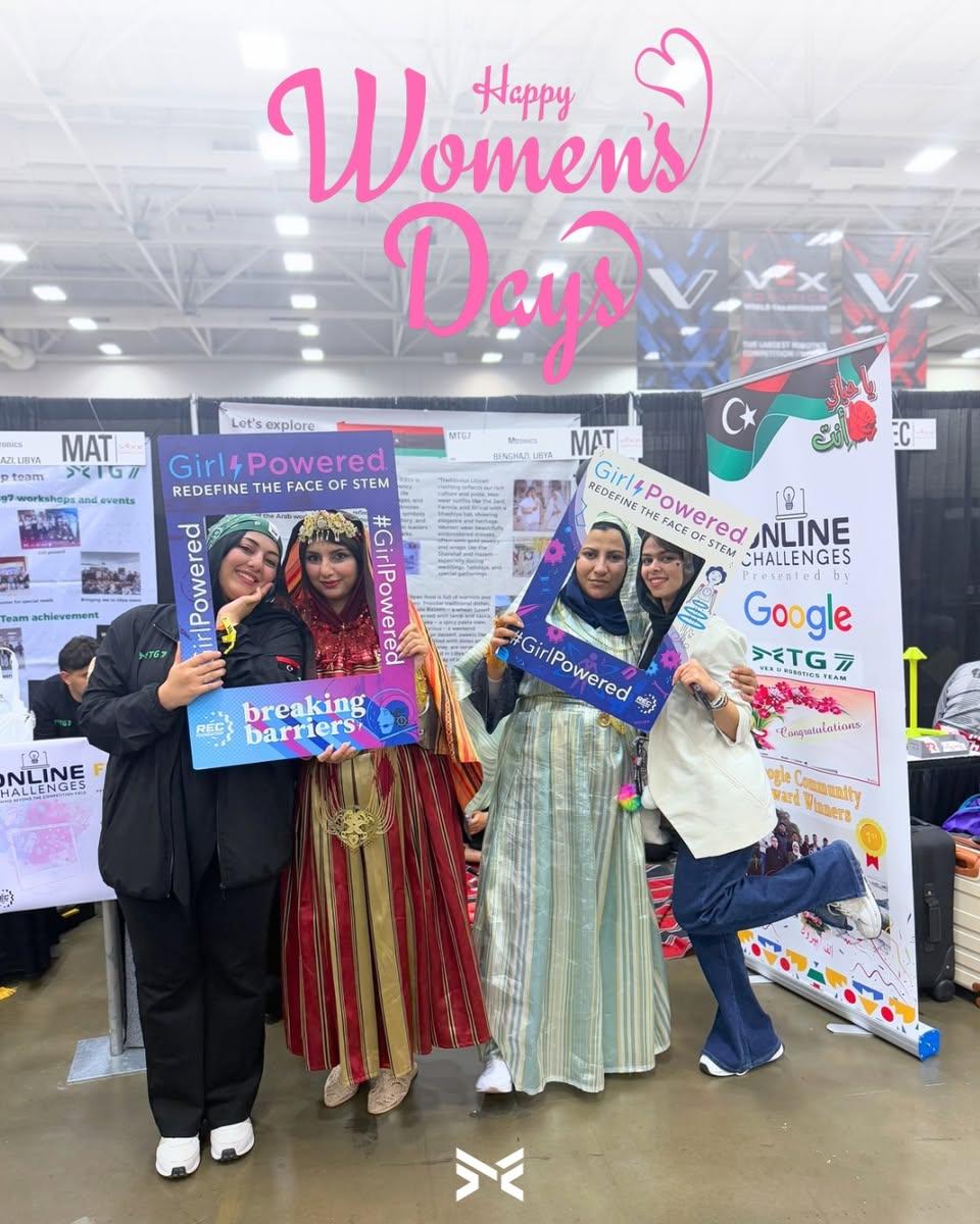 أربع شابات، اثنتان منهن بالزي التقليدي، يحملن إطارات تصوير Girl Powered في جناح الفريق.